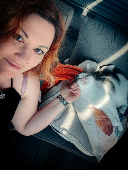 Selfie mit der Katze, sie liegt auf drei Kissen und einer Decke 